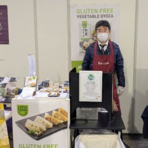 プレミアム・フードショー2025のヴィーガンセレクションで、グルテンフリーの野菜餃子を紹介する出展事業者のブース