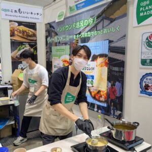 プレミアム・フードショー2025のヴィーガンセレクションで、ヴィーガンチーズを使った料理を実演する六甲バター株式会社のブース